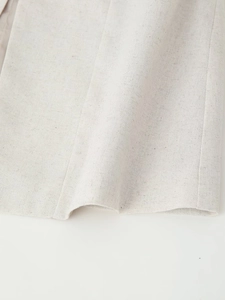 Detailed macro view of the breathable beige linen fabric texture and hem drape
