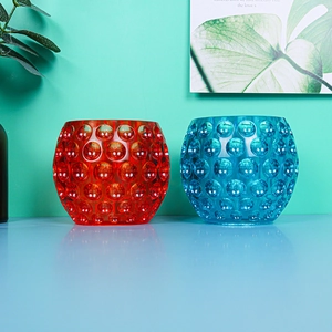 Detail of red and blue glass candle holders with raised polka dot textured patterns