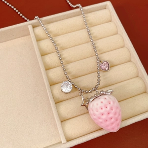 Detail view of pink strawberry necklace with silver ball chain and heart charms
