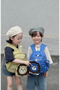Close-up of children wearing cute 3D cartoon lion backpacks in green and blue colors