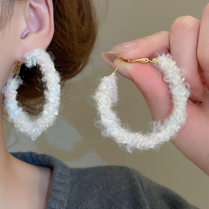 Gros plan de boucles d'oreilles créoles blanches en peluche avec paillettes irisées