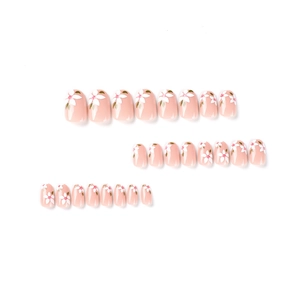 Pink press-on nails set with delicate white floral designs and green leaf accents
