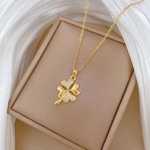 Macro shot of gold four-leaf clover necklace with sparkling inlaid stones in jewelry box