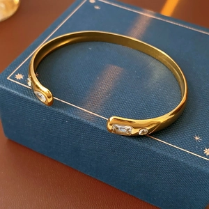 Macro detail of a gold open bangle with white zircons on a blue jewelry box