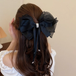 Close-up of black mesh bow hair clip with pearl and rhinestone fringe on model