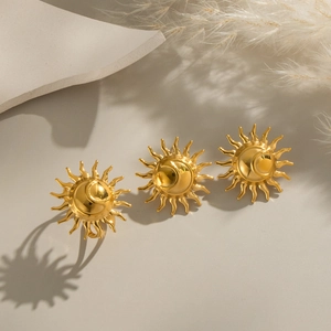 Detailed view of three golden sun-shaped stainless steel rings on a soft natural background