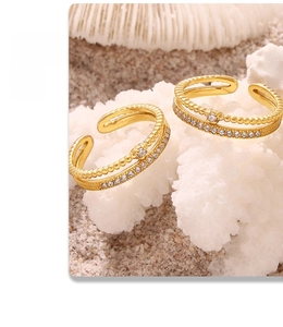 Dettaglio di due anelli placcati in oro 18k con zirconi incastonati su corallo bianco