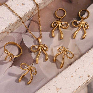 Detail view of 18K gold plated jewelry set featuring crystal bow necklace and ring