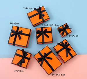 Top view of six orange jewelry gift boxes with black ribbons and size dimensions