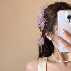 Détail d'une pince à cheveux fleur en tissu violet avec long pompon et perles