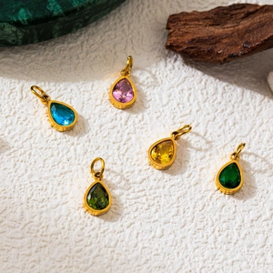 Detail of five 18K gold plated teardrop pendants with colorful birthstones on stone base