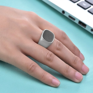 Minimalist matte silver signet ring with black square inlay worn on index finger