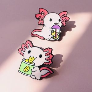 Gros plan de pins en émail axolotl avec thé aux perles et snacks sur fond rose