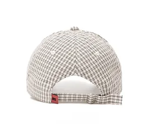 Detail of adjustable metal buckle and red label on black and white plaid baseball cap