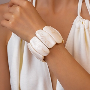 Close-up of a wide acrylic stretch bracelet with marbled ivory texture on a female wrist