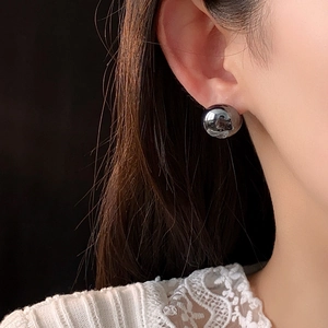 Close-up of a minimalist dark grey high-luster pearl stud earring worn on a model ear