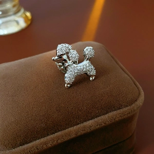 Macro shot of silver puppy brooch with zircons on brown velvet box showing details