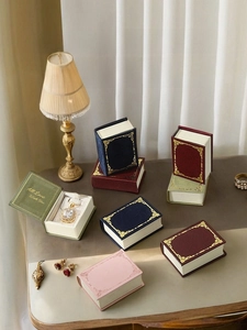 Detailed view of vintage book-shaped jewelry boxes with gold foil patterns and velvet lining