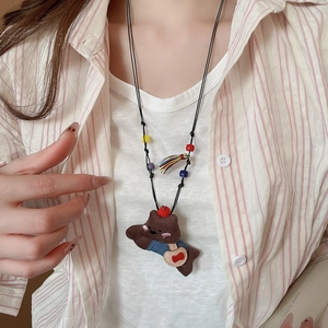 Detail of cute brown plush bear pendant necklace with colorful beads and tassels on a model