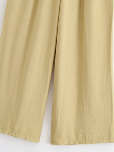 Gros plan détaillé du pantalon large jaune clair montrant la texture du lin naturel