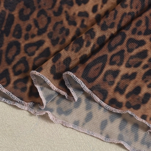 Detailed macro view of leopard print mesh fabric texture with fine overlock stitching edges