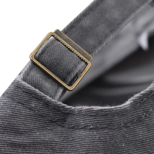 Close-up of bronze adjustable metal buckle on dark gray washed cotton baseball cap