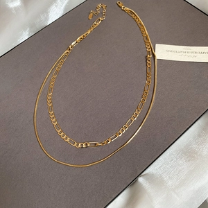 Detail of layered 18k gold plated necklace with Figaro chain and lobster clasp
