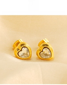 Detailed macro shot of heart-shaped gold titanium earrings with clear crystal inlay