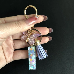 Purple resin keychain with gold ring, tassel, and heart sequins detail on black background
