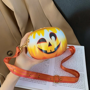 Detail of pumpkin shaped crossbody bag with smiling face and adjustable striped strap
