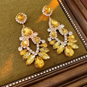 Detail of gold water-drop tassel earrings with crystal pavé on green velvet cushion