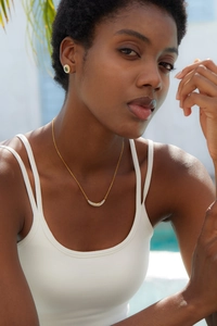 Model wearing a 925 silver 18K gold crescent necklace with diamonds and green stud earrings