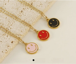Detailed close-up of pink and red enamel smiley face pendants on gold stainless steel chains