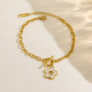 Vue macro d'une chaîne en acier plaqué or 14K avec un délicat pendentif fleur blanche