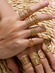 Close-up of bohemian gold-plated leaf and geometric rings stacked on a model's hand