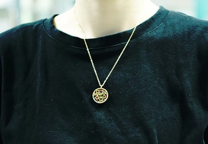Close-up of a golden round hollow pendant necklace featuring MAMA and star details