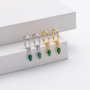 Macro detail of S925 silver and gold earrings with pear-cut green zircon stones
