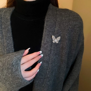 Macro shot of silver butterfly brooch with teardrop zircons on a gray cardigan
