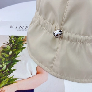 Close-up of beige bucket hat with adjustable silver metal buckle and fabric texture