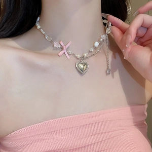 Détail du collier perles et métal avec pendentif cœur et nœud rose sur modèle