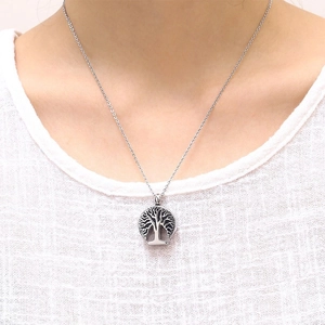 Close-up of a silver Tree of Life urn pendant necklace worn by a fashion model