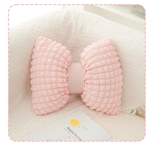 Detail of pink bow-shaped pillow with textured bubble fabric on white tassel blanket