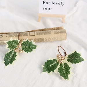 Weihnachts-Serviettenring mit Stechpalmenblättern und Goldbeeren auf weißem Textilhintergrund