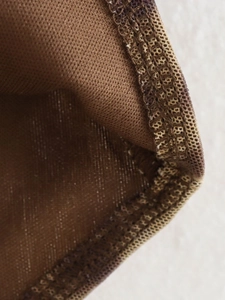Macro detail of the brown knit fabric showing professional stitching and mesh texture