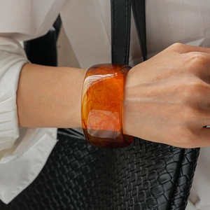 Close-up of translucent amber resin bangle with marbled texture on a model's wrist