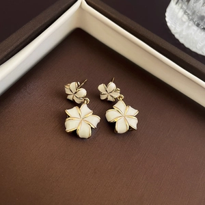 Macro shot of white five-petal flower earrings with gold plating in a jewelry box