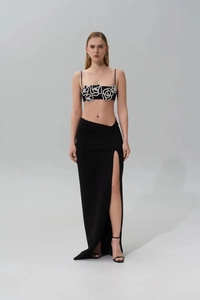 Detail of black slim-fit set featuring silver sequin rose and high slit maxi skirt