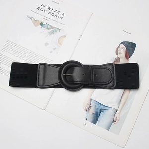 Detail view of a black elastic waist belt with a round faux leather buckle on a magazine