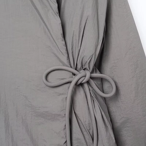 Detalle de textura plisada gris con cordón ajustable en la cintura de la prenda
