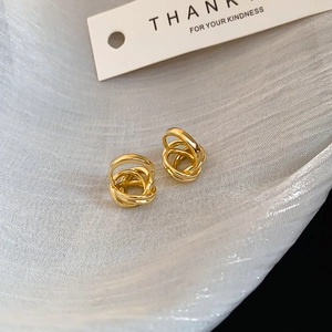 Close-up of golden multi-layer twisted hoop earrings on soft textured white fabric